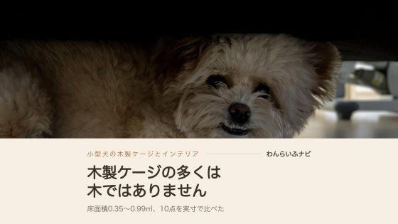 ソファの下の狭い暗がりに寝そべって、こちらを見ているポメプーのパフィ